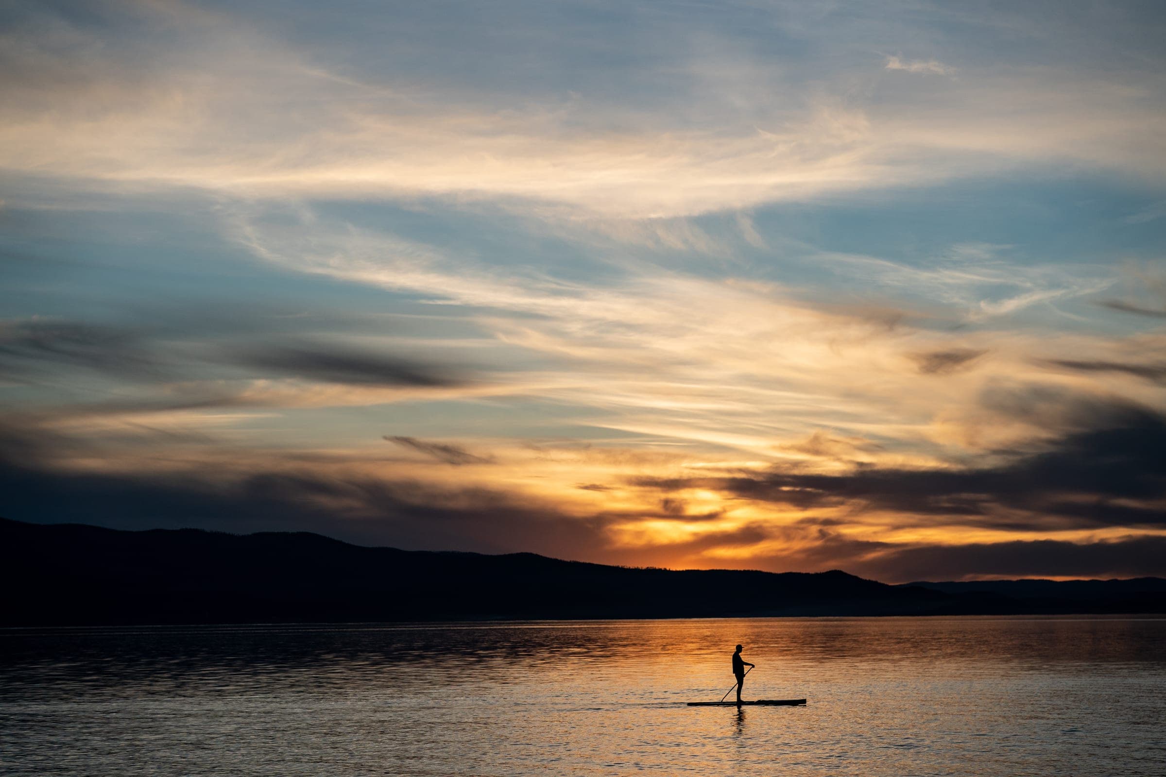Paddleboarder silhouetted on Flathead Lake at sunset