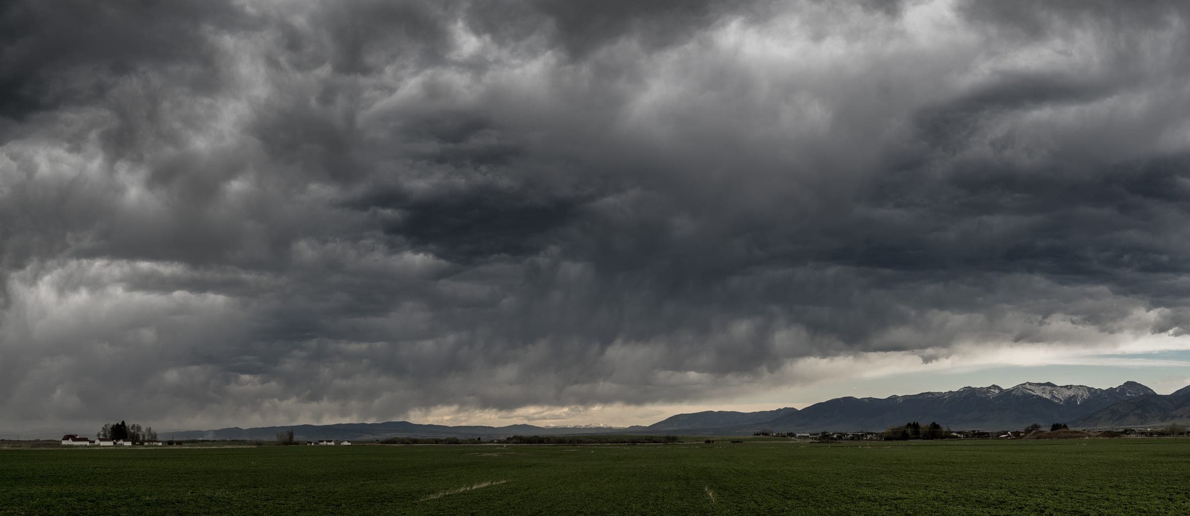 Storm clouds stacked over green Gallatin Valley fields