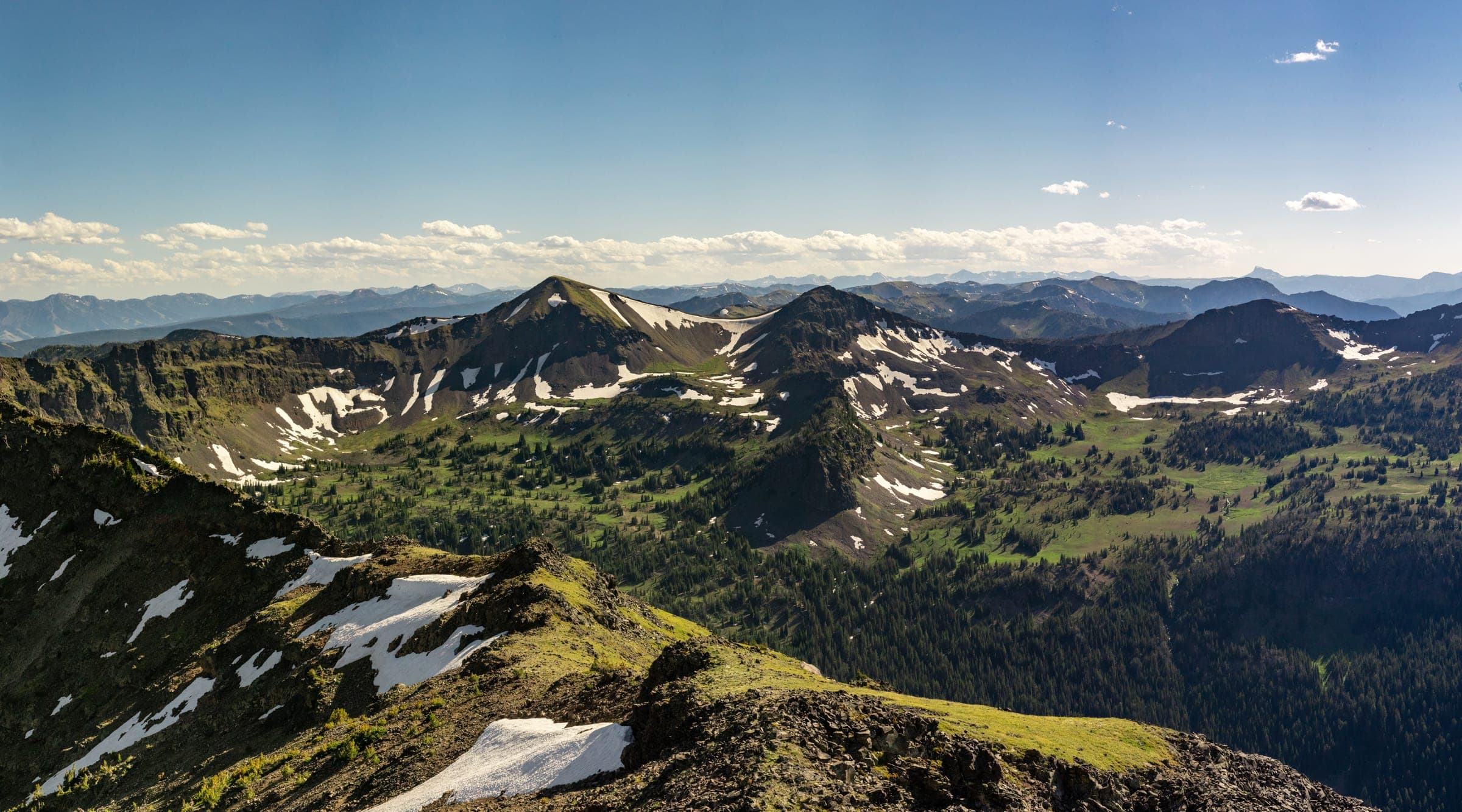 Green alpine ridges and snowfields rolling to the horizon