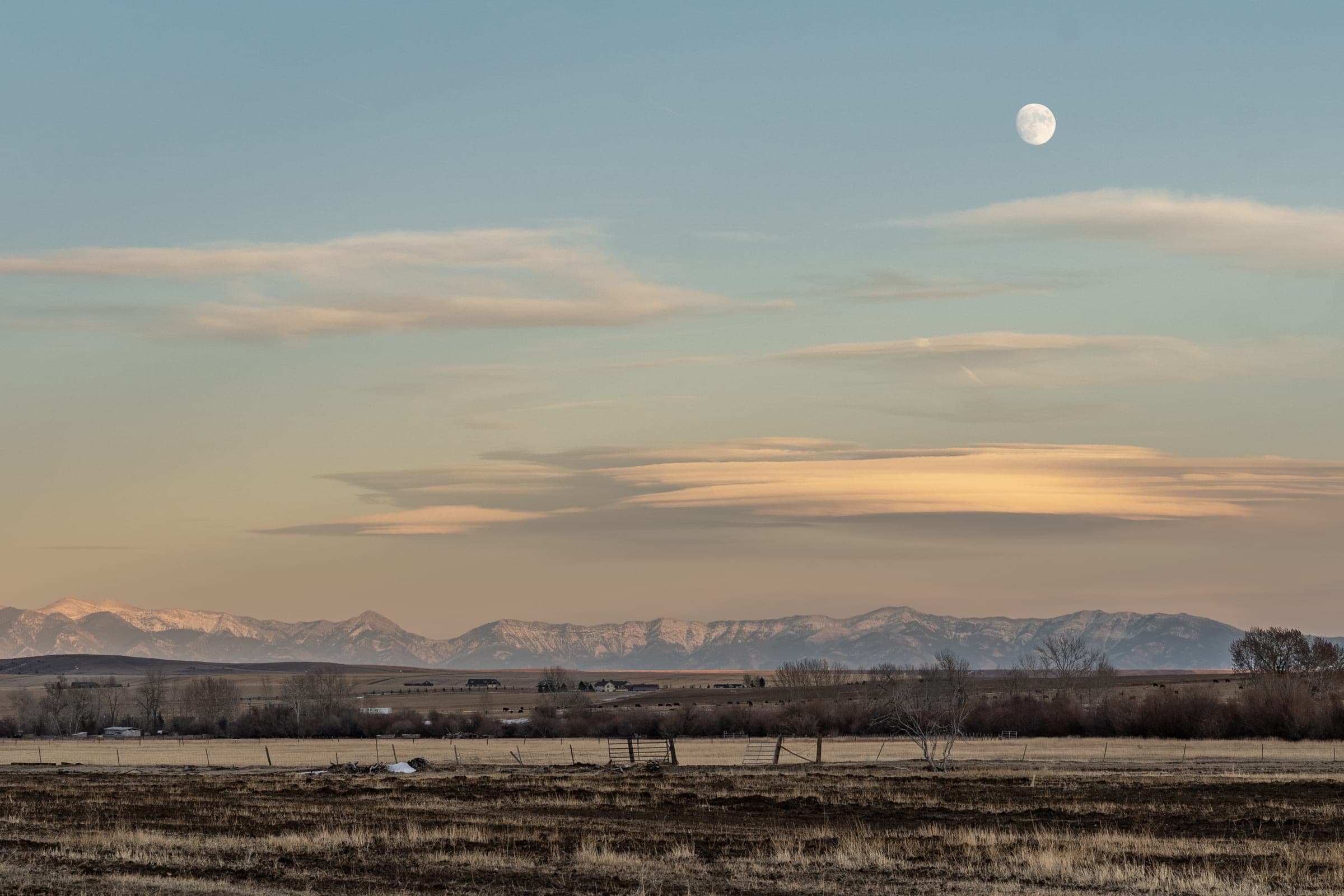 Moon rising over a snow-capped range and frosty ranchland