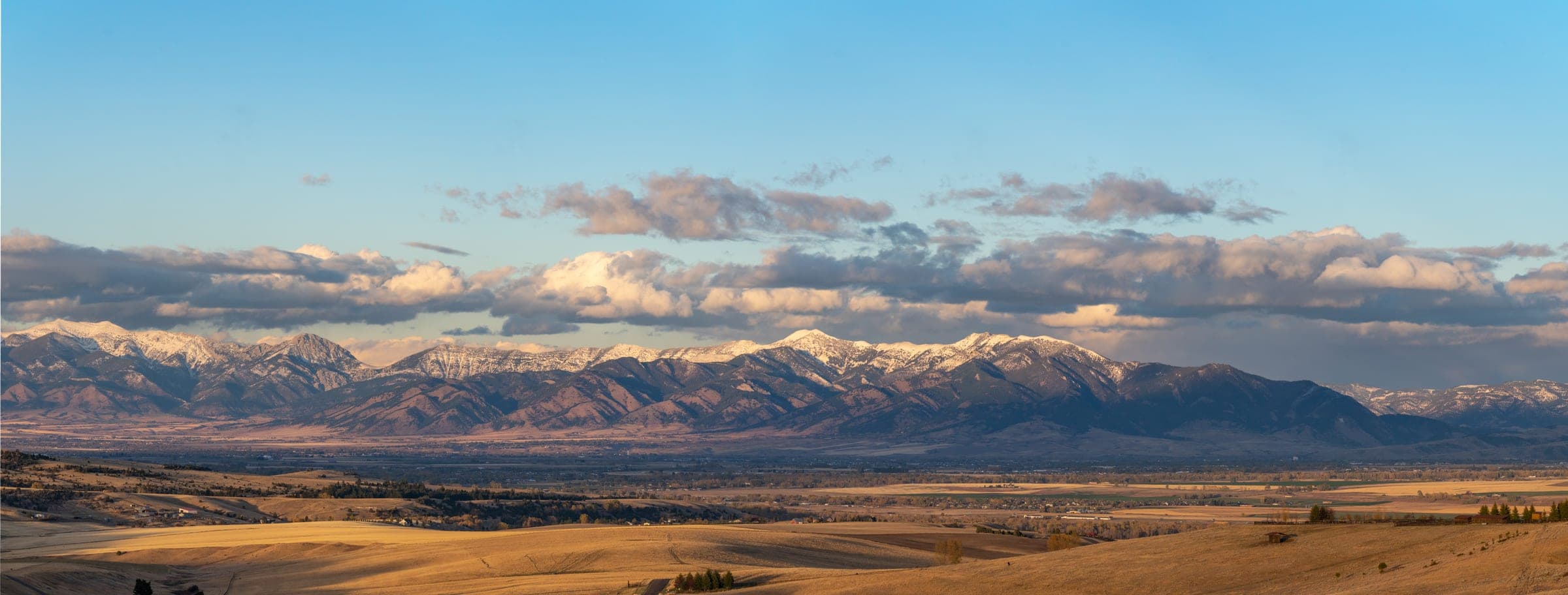 Snowy range above a golden valley under drifting clouds