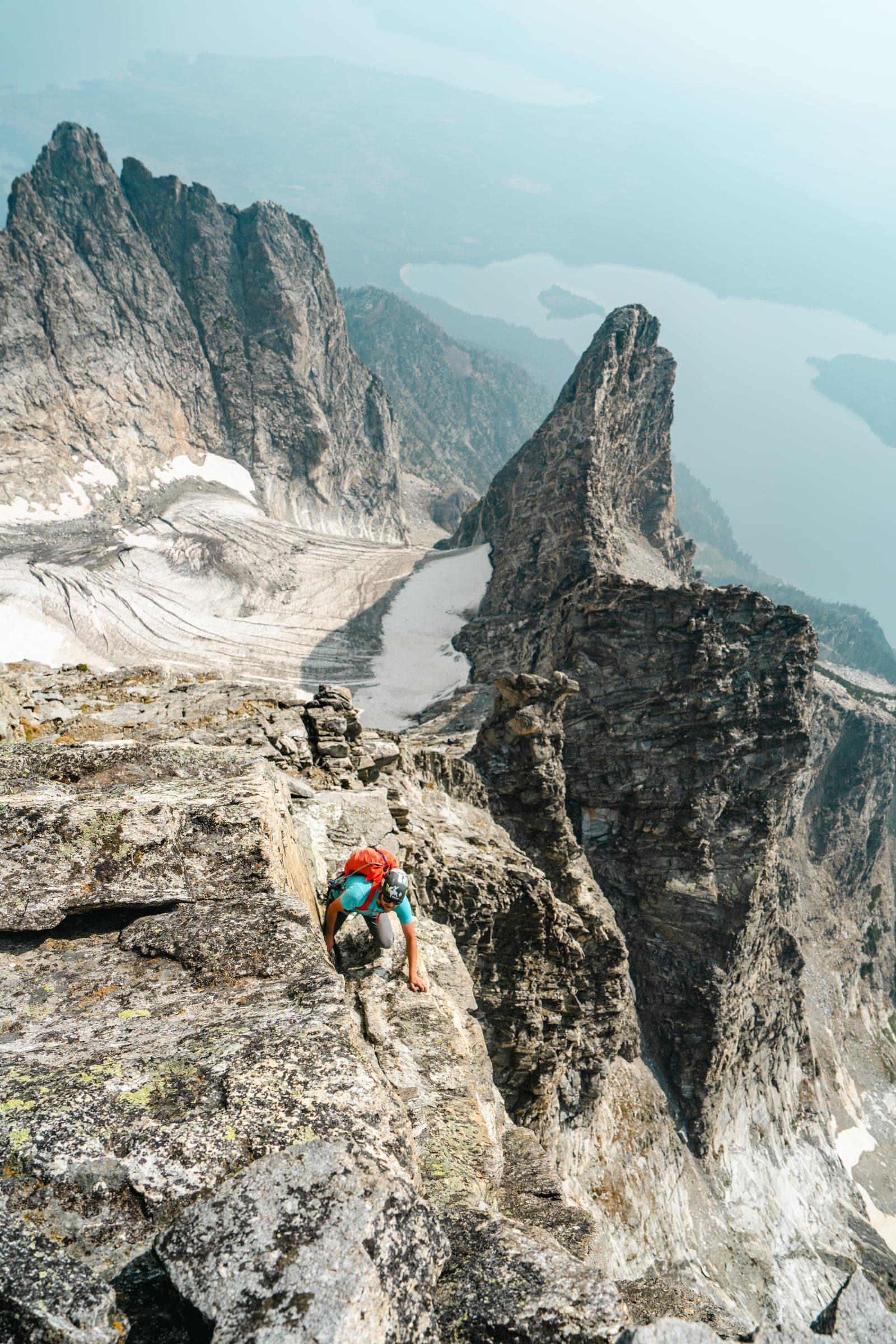Climber on a granite ridge with glacier and spire behind