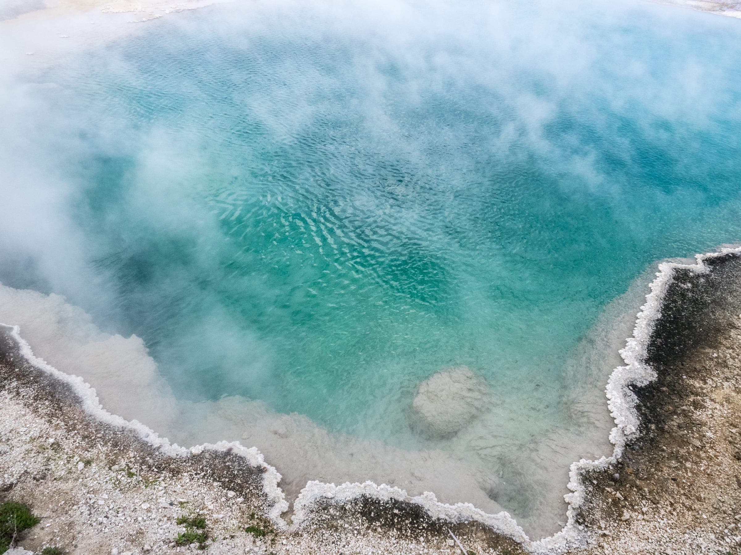 Steaming turquoise Yellowstone hot spring with crusted rim