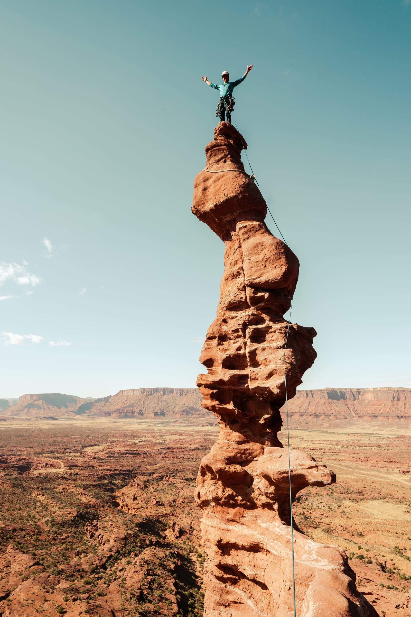 Climber with arms raised atop a twisting desert tower