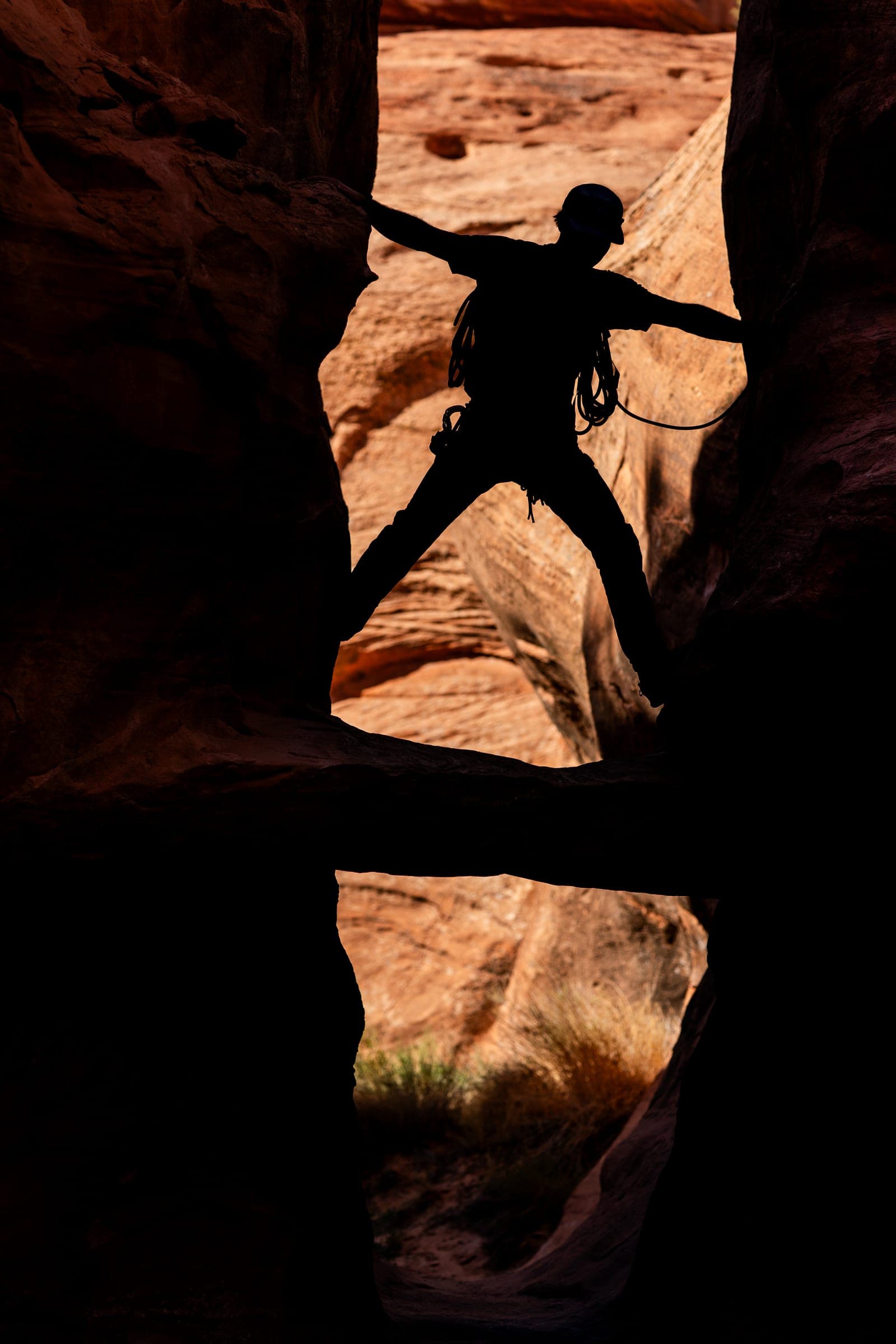 Climber silhouetted stemming a sandstone slot