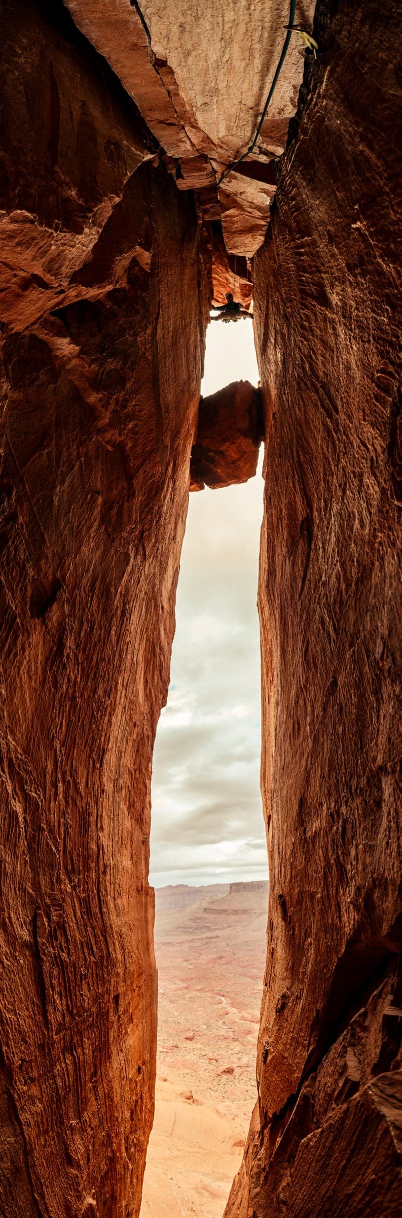 Looking up a narrow sandstone chimney to a sliver of sky
