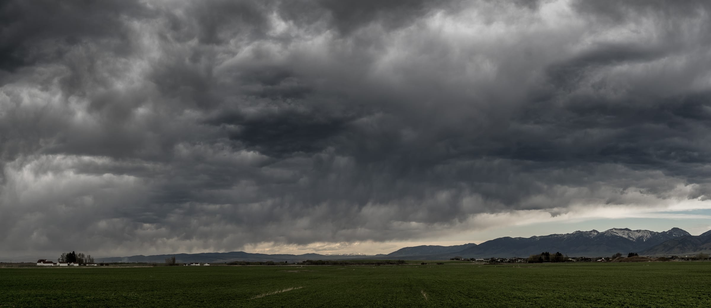 Storm clouds stacked over green Gallatin Valley fields