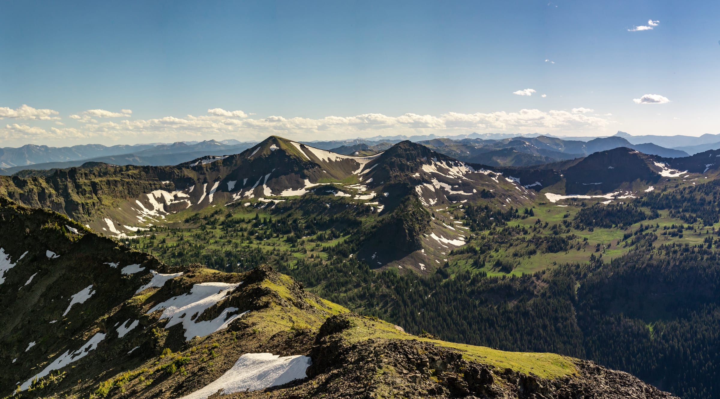 Green alpine ridges and snowfields rolling to the horizon