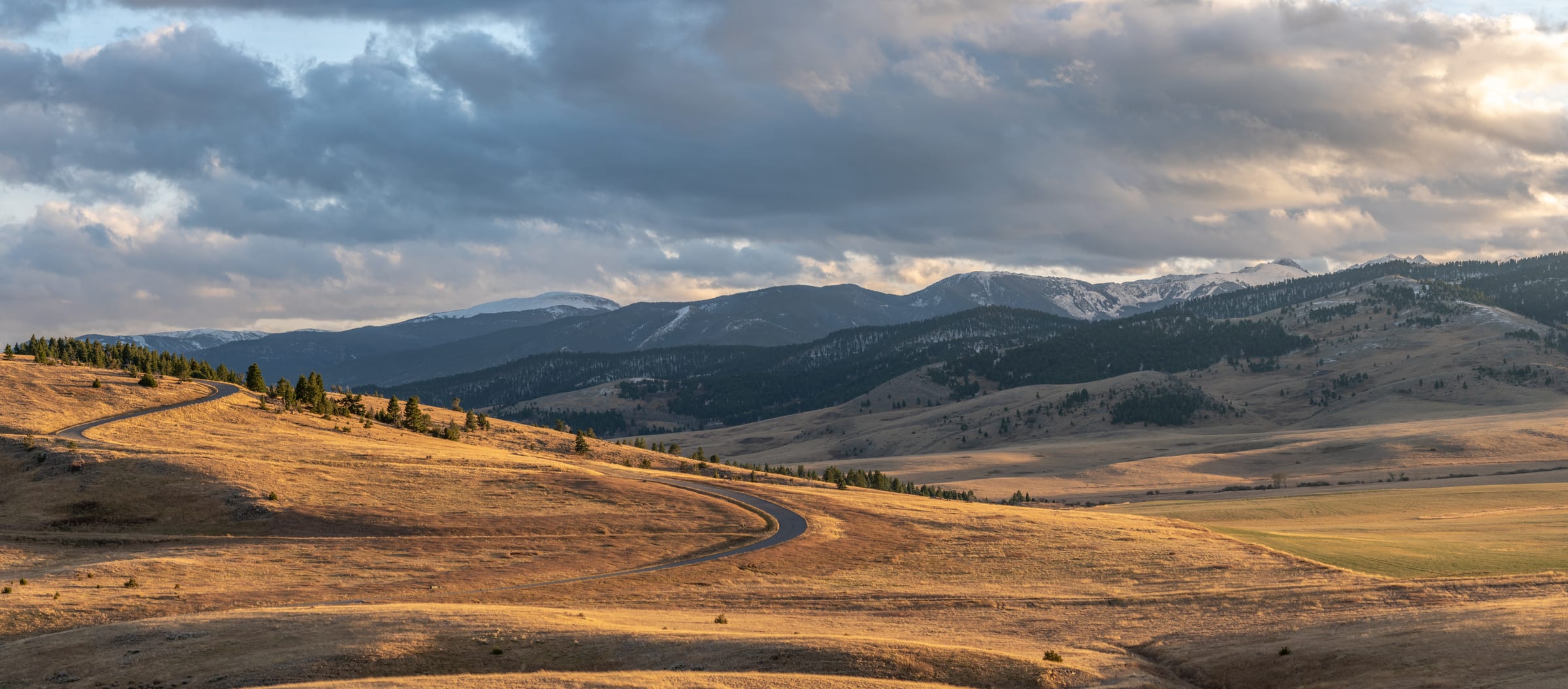 Road winding through golden hills under storm light