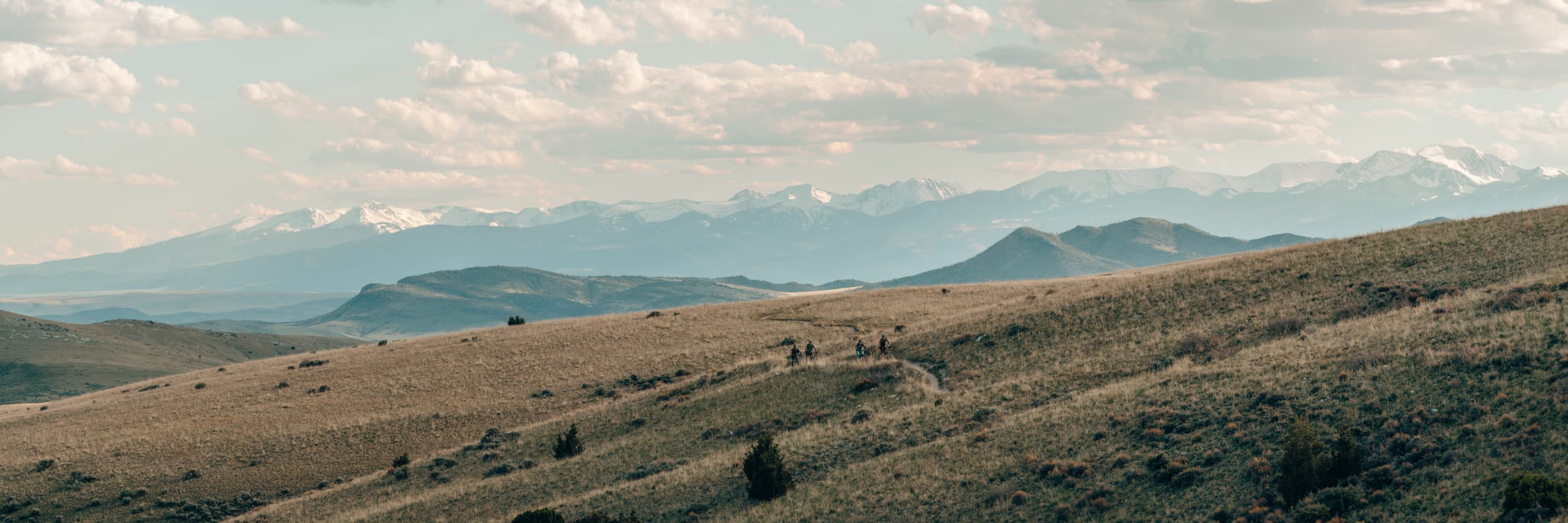 Riders strung along a golden hillside trail below the Crazy Mountains