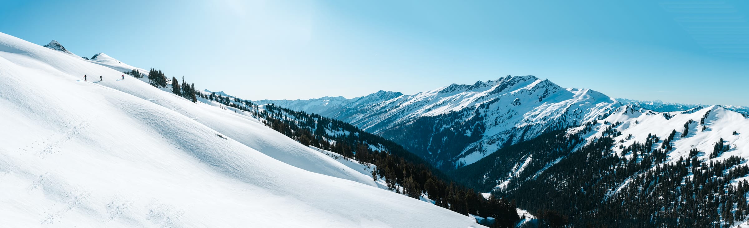 Ski tourers crossing a huge snowfield above a deep valley, Glacier Peak