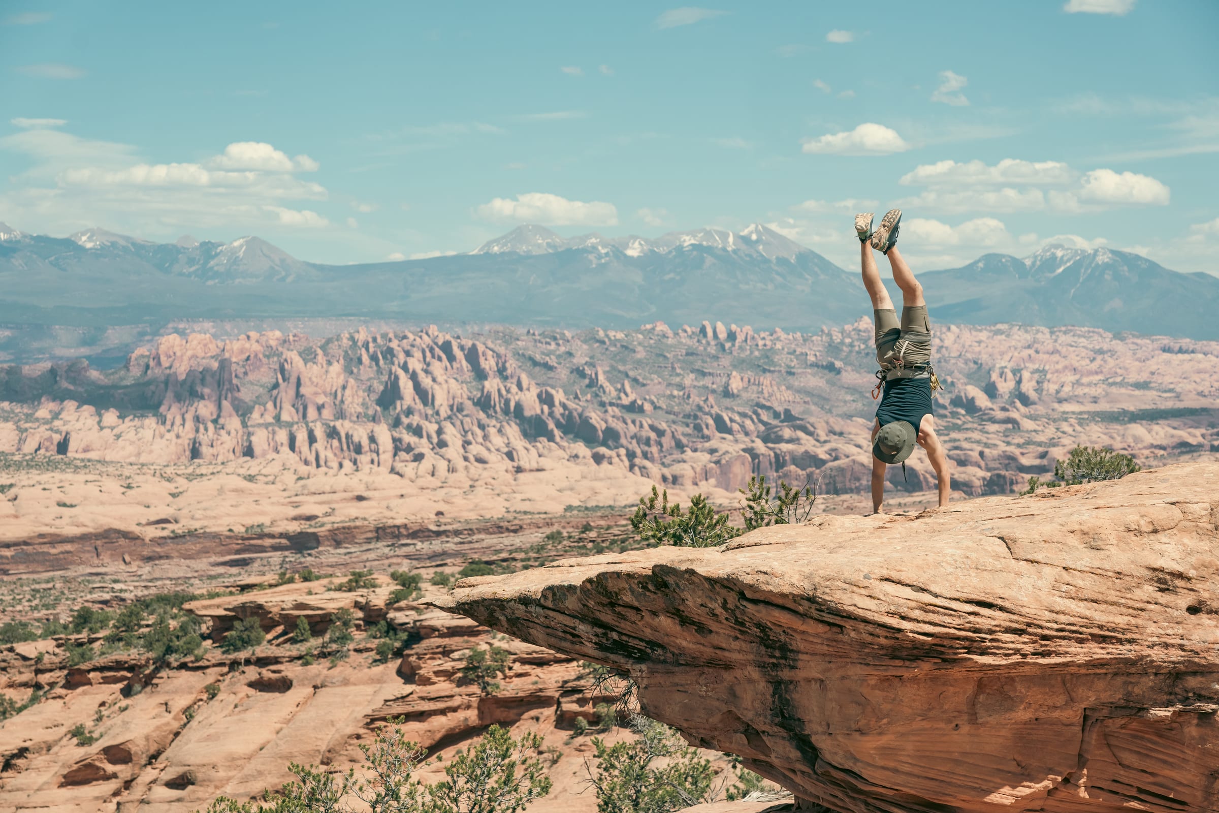 Handstand on a slickrock ledge above Moab with snowy La Sals