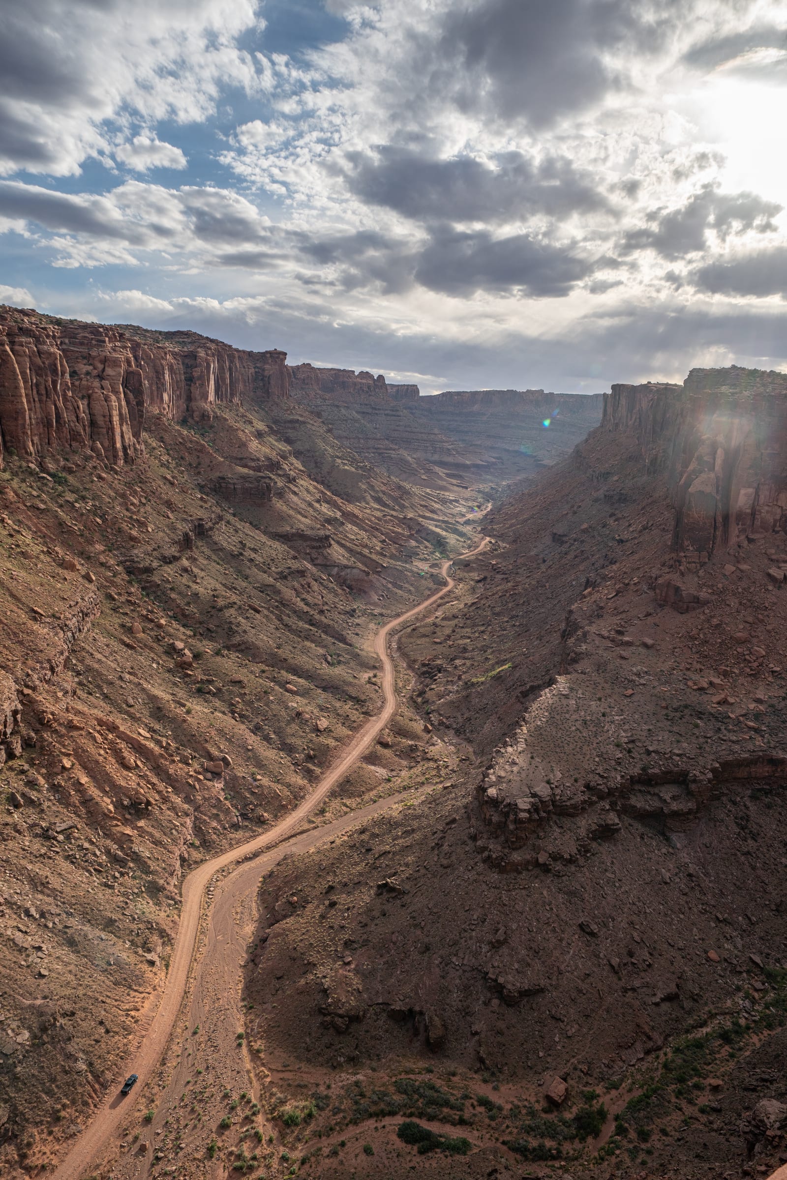 Dirt road threading a Moab canyon under storm clouds